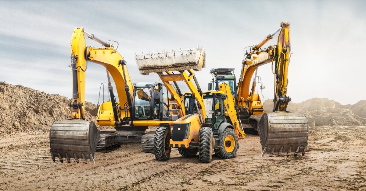 Three different pieces of mining equipment drive on a dirt landscape with different tread patterns all around them.