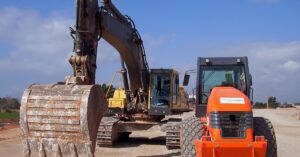 Two heavy-duty mining vehicles parked at an outdoor site. One is an excavator, and the other is a tractor.