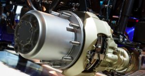 A close-up of an oversized wheel hub for heavy machinery. The equipment is elevated inside an enclosed facility.