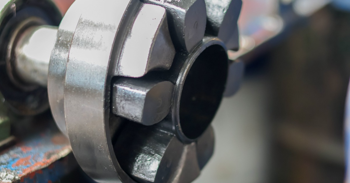 A close-up of a metal flexible shaft coupling with block segments and a central circular opening on a machine.