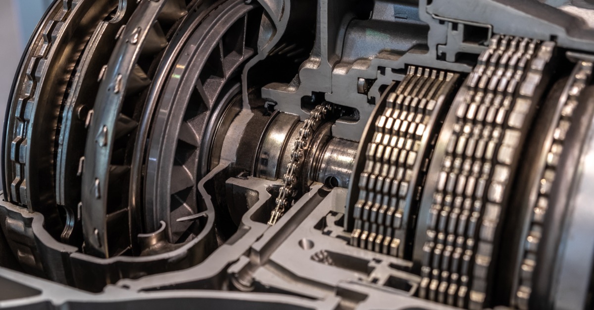 A close-up of a cutaway transmission showing a torque converter, shafts, and stacked metal gear discs.